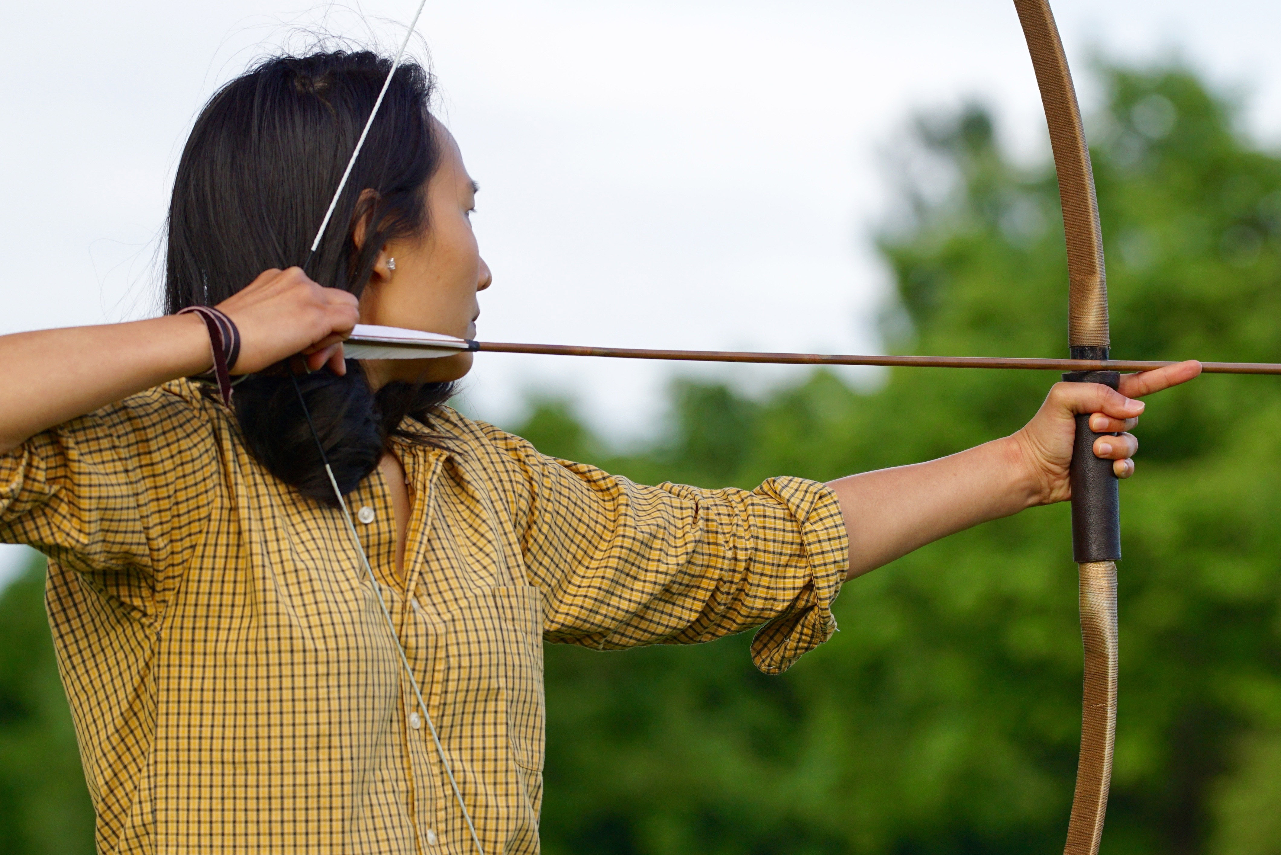 Female archer drawing back bow